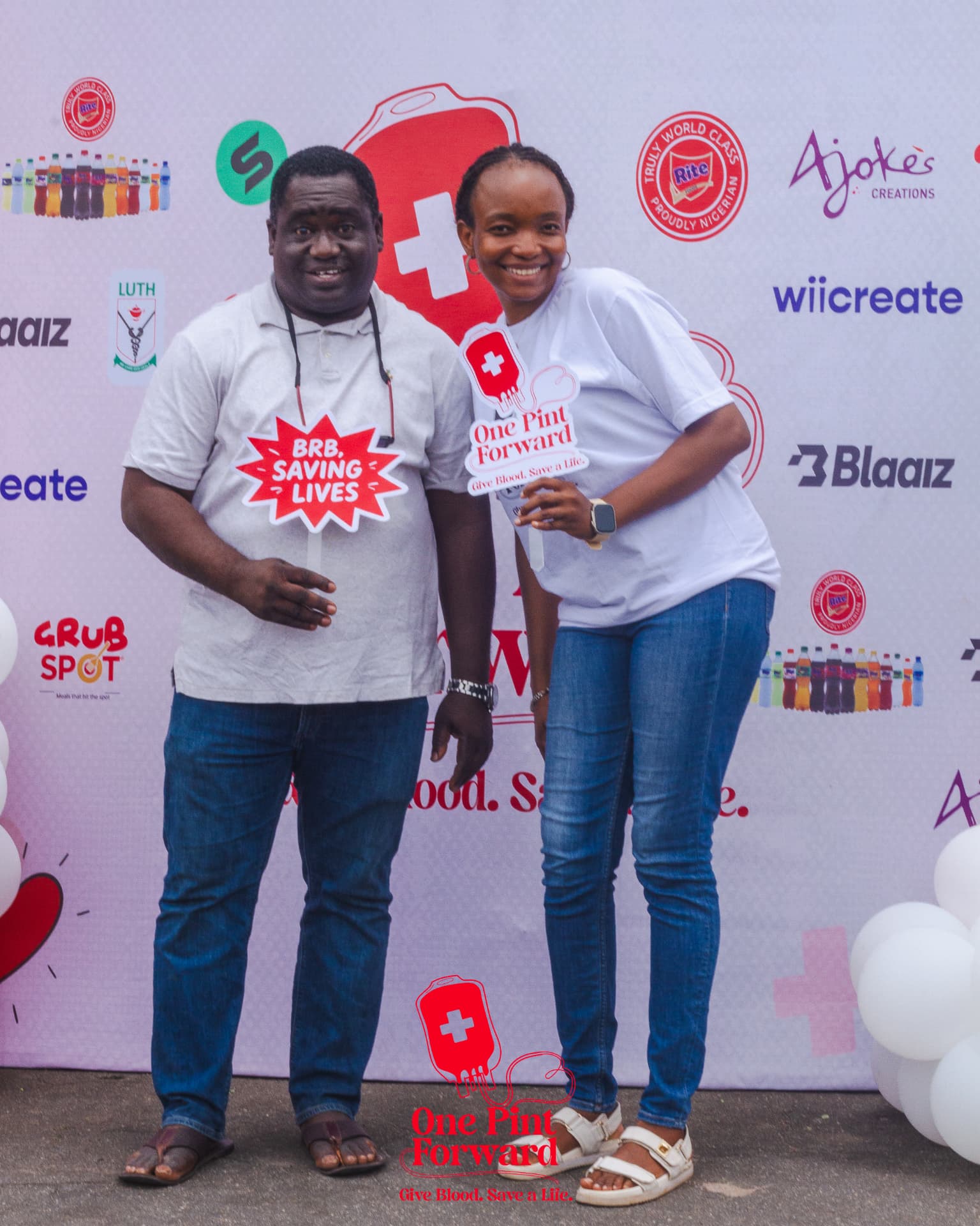 Two supporters posing with One Pint Forward and BRB, Saving Lives photo props